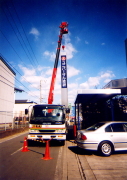 看板　作業車　４ｔユニック車のクレーンで看板を吊り上げ、これから建植。